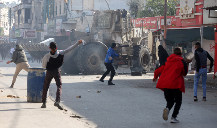 Palestinos atiram pedras em meio a confrontos com tropas israelenses durante incursão em Jenin, na Cisjordânia, em 26 de janeiro (EFE/EPA/ALAA BADARNEH)