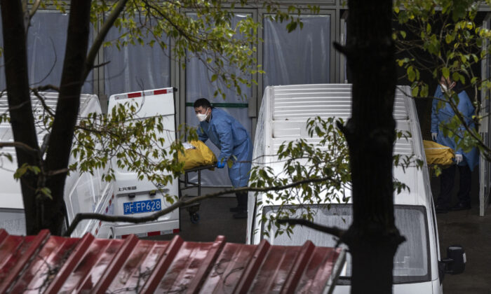 Trabalhadores funerários carregam corpos em vans para serem levados para cremação em uma movimentada funerária local em Xangai em 13 de janeiro de 2023. (Kevin Frayer/Getty Images)