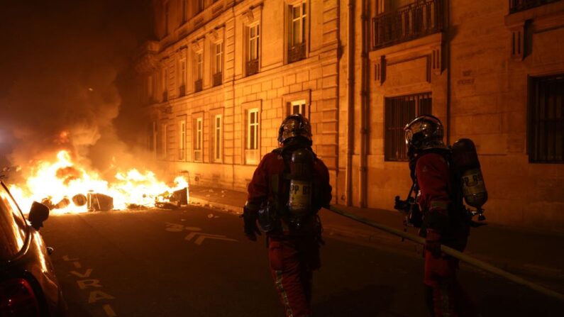 Bombeiros franceses operam um incêndio durante uma manifestação perto da Place de la Concorde depois que o governo francês promoveu uma reforma das pensões no parlamento sem votação, usando o artigo 49,3 da constituição, em Paris em 16 de março de 2023 (Foto de THOMAS SAMSON / AFP via Getty Images)