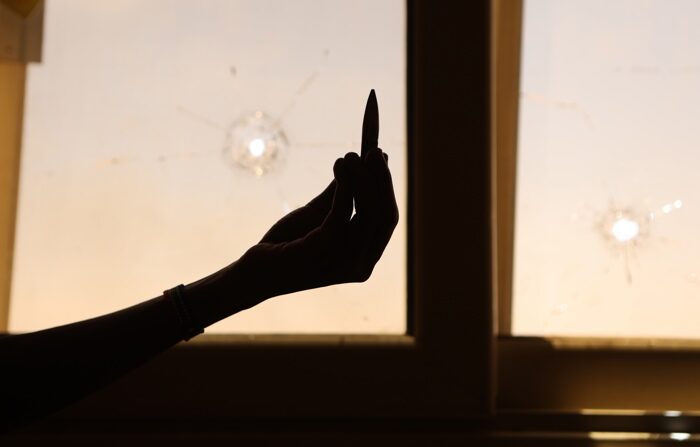 Um civil segura uma caixa de bala vazia em frente a uma janela danificada de um prédio residencial durante a escaramuça entre o exército sudanês e os paramilitares das Forças de Apoio Rápido (RAF) em Cartum, Sudão, 18 de abril de 2023 (EFE/EPA/STRINGER)