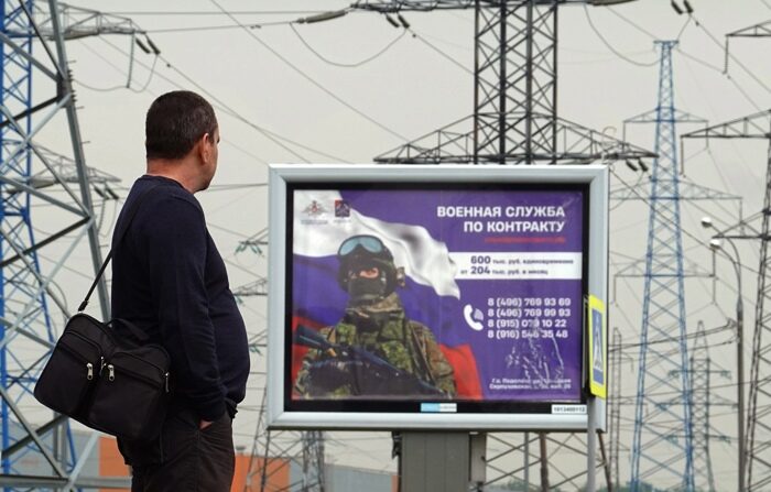 Um homem em frente a um outdoor em apoio às forças armadas russas onde se lê 'Contract service', nos arredores de Moscou, Rússia, 25 de maio de 2023 (EFE/EPA/MAXIM SHIPENKOV)