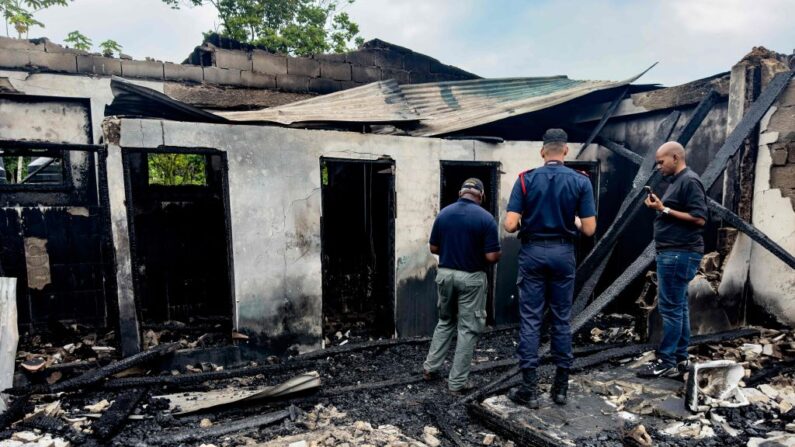 Investigadores e funcionários do governo inspecionam o dormitório da escola onde um incêndio matou pelo menos 19 pessoas em Mahdia, Guiana, em 22 de maio de 2023 (Foto de KENO GEORGE/AFP via Getty Images)