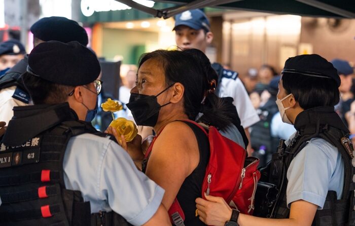 A polícia discute com a ativista pró-democracia Chan Po-ying (C), esposa de Leung Kwok-hung, mais conhecido como 'Cabelo Comprido', ao parar e revistá-la em uma área comercial perto de Victoria Park em Hong Kong, China, 04 de junho de 2023 (EFE/EPA/BERTHA WANG)