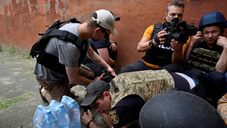 Pessoas se protegem de bombardeios durante evacuação de uma área inundada na área de Kherson, em 8 de junho de 2023, após danos sofridos na barragem da usina hidrelétrica de Kakhovka (Foto de SERGEI CHUZAVKOV/AFP via Getty Images)