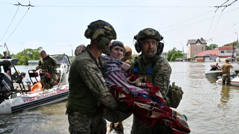 Militares ucranianos ajudam a descarregar um residente local deficiente de um barco durante uma evacuação de uma área inundada em Kherson em 8 de junho de 2023, após danos sofridos na barragem da usina hidrelétrica de Kakhovka (Foto de GENYA SAVILOV/AFP via Getty Images)