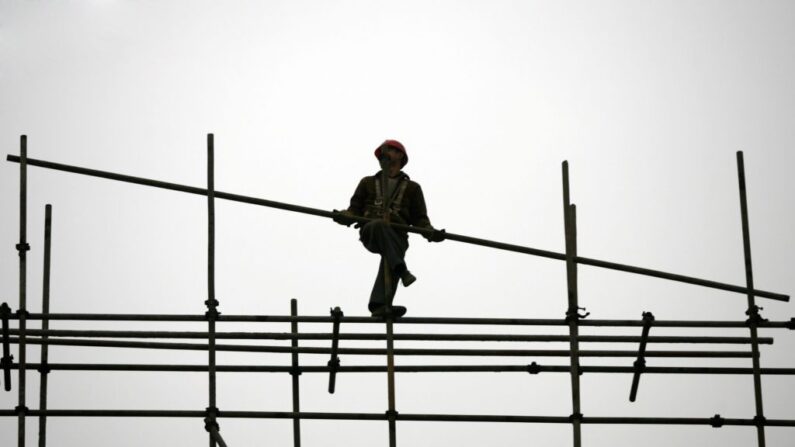 Um trabalhador migrante ergue andaimes em um canteiro de obras no município de Chongqing, China, em 13 de janeiro de 2007. (China Photos/Getty Images)