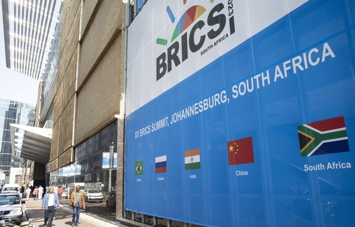 Pessoas passam por uma faixa durante os preparativos finais para a 15ª Cúpula do BRICS no Centro de Convenções de Sandton, Joanesburgo, África do Sul, 20 de agosto de 2023 (EFE/EPA/KIM LUDBROOK)