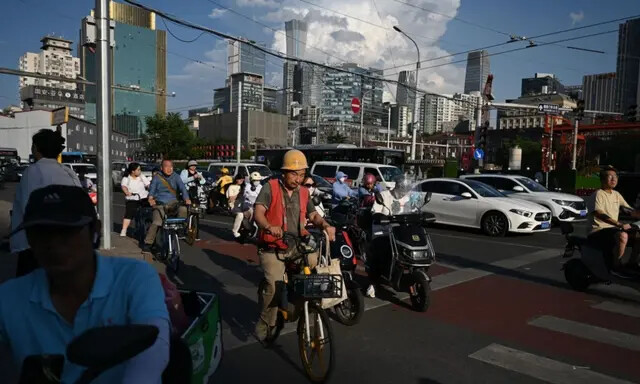 Pessoas esperam para atravessar uma rua em Pequim em 20 de junho de 2023 (Greg Baker/AFP via Getty Images)