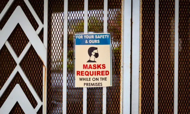Uma placa solicitando que as pessoas usem máscaras está pendurada em uma porta em Tustin, Califórnia, em 10 de março de 2021. (John Fredricks/The Epoch Times)
