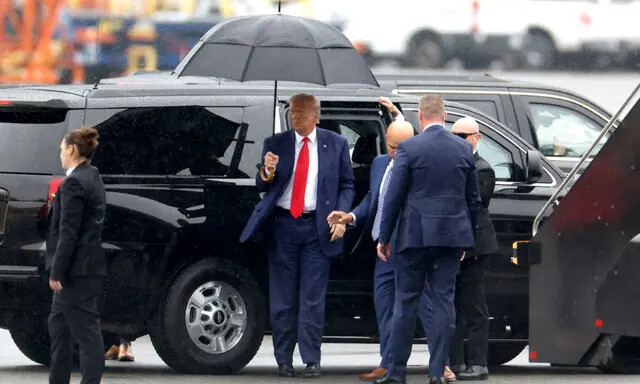 O ex-presidente dos EUA, Donald Trump, segura um guarda-chuva ao chegar ao Aeroporto Nacional Reagan após uma acusação em um tribunal de Washington, DC em Arlington, Virgínia, em 3 de agosto de 2023. (Tasos Katopodis/Getty Images)