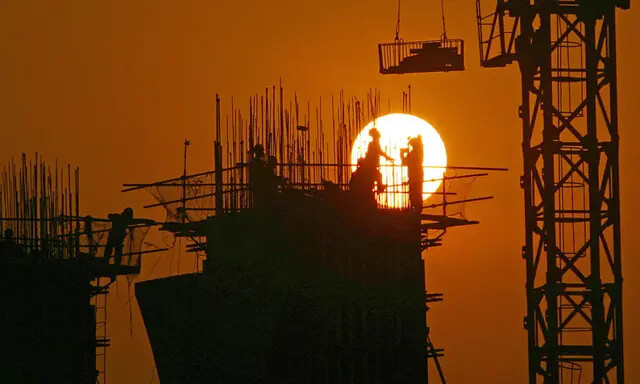 Trabalhadores chineses trabalham em um canteiro de obras ao pôr do sol em Chongqing, China, em 6 de março de 2005. (China Photos/Getty Images)