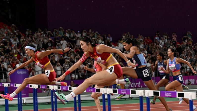 A chinesa Lin Yuwei (E) e a chinesa Wu Yanni (C) competem na prova final de atletismo dos 100m com barreiras femininos durante os Jogos Asiáticos de 2022 em Hangzhou, na província oriental de Zhejiang, na China, em 1º de outubro de 2023 (Foto de WILLIAM WEST/AFP via Getty Images)