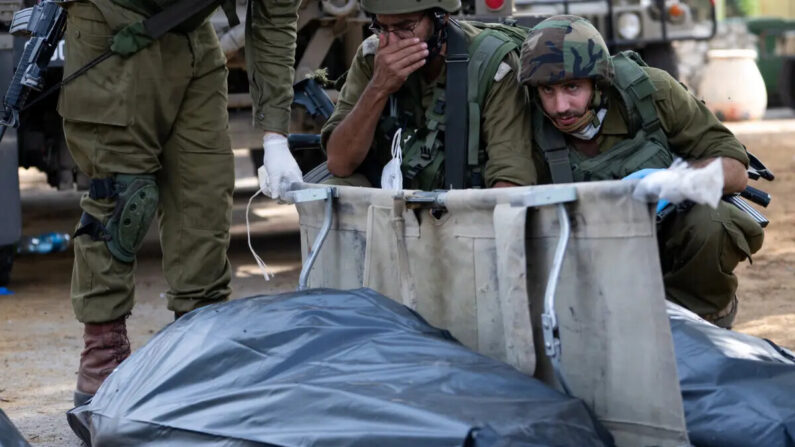 Um soldado das Forças de Defesa de Israel reage e cobre o rosto antes de remover o corpo de um civil morto dias antes em um ataque de terroristas do Hamas em 10 de outubro de 2023, em Kfar Aza, Israel (Alexi J. Rosenfeld/Imagens Getty)