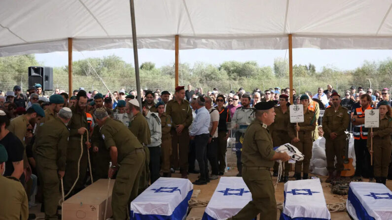 Pessoas choram junto aos caixões de cinco membros da família Kutz que foram mortos em um ataque terrorista palestino em seu kibutz de Kfar Aza, durante seu funeral na cidade de Gan Yavne, no centro de Israel, em 17 de outubro de 2023 (Oren Ziv/AFP através da Getty Images)