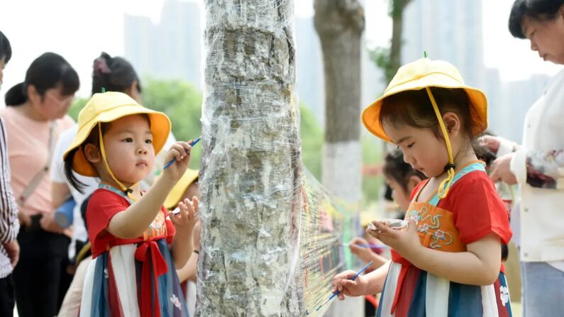 Crianças pintam em uma folha de plástico em um parque no Dia Internacional da Criança em Haian, na província de Jiangsu, leste da China, em 1º de junho de 2022. (STR/AFP via Getty Images )
