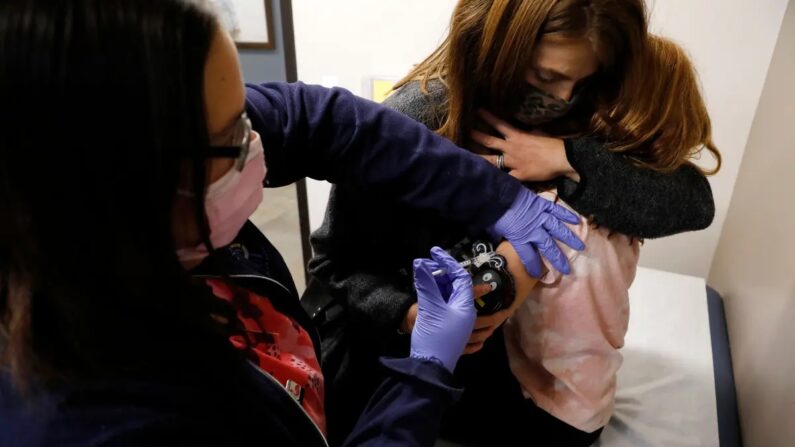 Uma criança de 6 anos é consolada por sua mãe ao receber sua primeira dose da vacina Pfizer-BioNTech Covid-19 em Novi, Michigan, em 3 de novembro de 2021 (Jeff Kowalsky/AFP via Getty Images)
