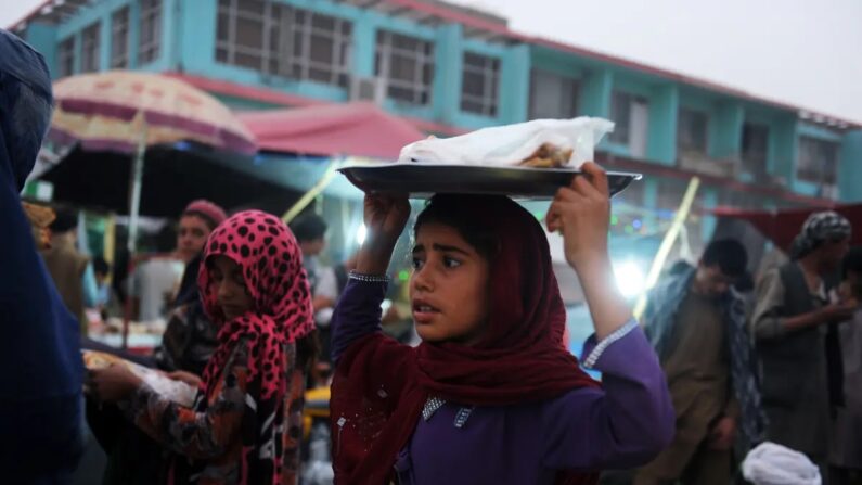 Uma menina afegã vende um pão achatado típico afegão nas ruas de Mazar-i-Sharif em 1º de julho de 2014. (Farshad Usyan/AFP/Getty Images)