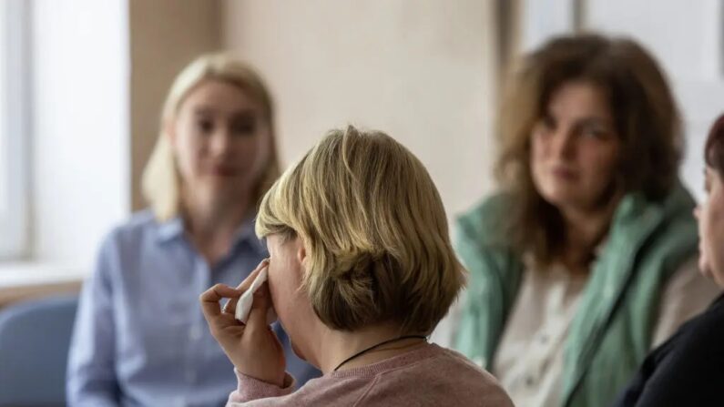 Uma mulher deslocada pela guerra enxuga lágrimas durante uma sessão de aconselhamento enquanto dois psicólogos ouvem em Kryvyi Rih, Ucrânia, em 3 de maio de 2022. (John Moore/Getty Images)
