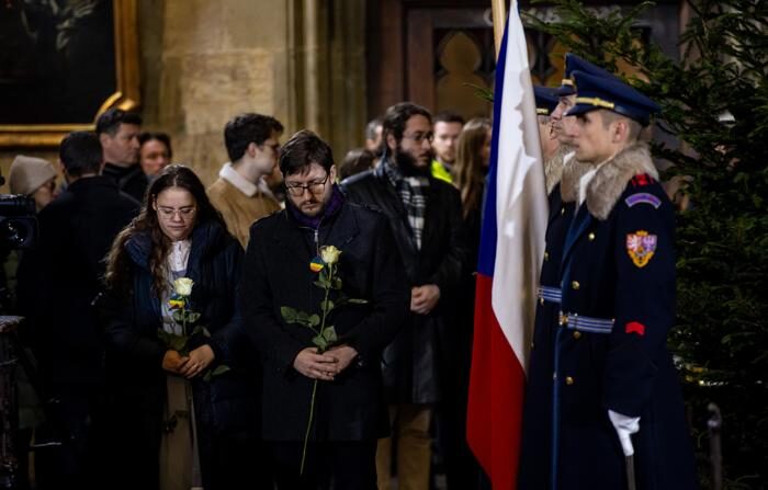 Um casal de cidadãos com rosas brancas assiste à cerimônia fúnebre na Catedral de São Vito, no sábado, em memória das vítimas do tiroteio na Faculdade de Filosofia de Praga, que matou 15 pessoas, incluindo o agressor, na quinta-feira. (EFE/ Martin Divisek)