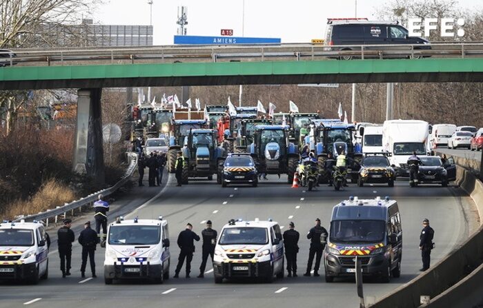 Policiais vigiam dezenas de tratores que participam de uma manifestação na autoestrada A15, perto de Argenteuil, ao norte de Paris, na França, na segunda-feira (EFE/Yoan Valat).