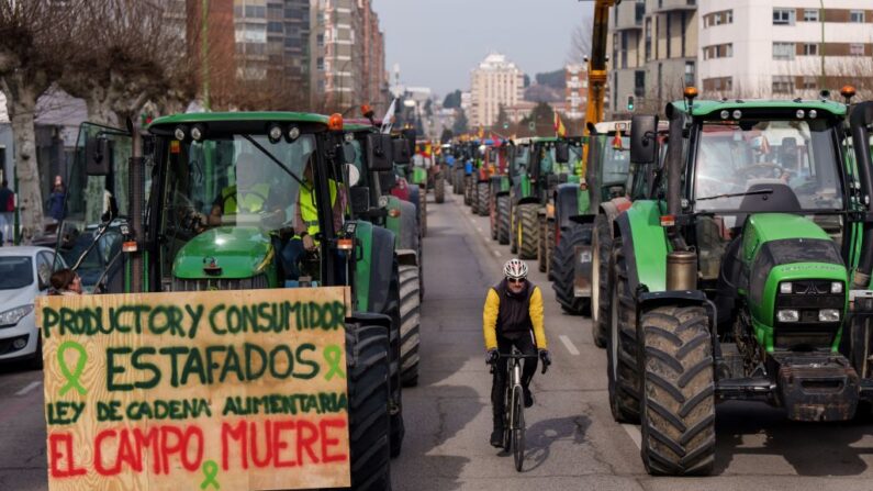 Agricultores espanhóis dirigem seu trator com um cartaz que diz "Produtores e consumidores defraudados, lei da cadeia alimentar, o campo morre" durante um protesto para exigir condições justas para o setor agrícola, em Burgos, norte da Espanha, em 6 de fevereiro de 2024 (Foto de CESAR MANSO/AFP via Getty Images)