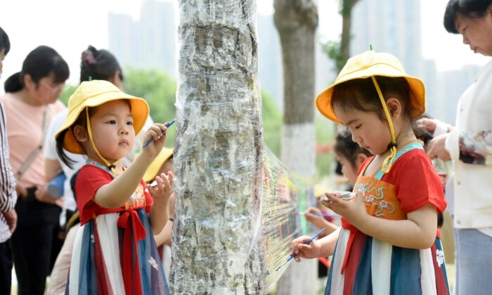 Crianças pintam em uma folha de plástico em um parque no Dia Internacional da Criança em Haian, Província de Jiangsu, leste da China, em 1º de junho de 2022. (STR/AFP via Getty Images)
