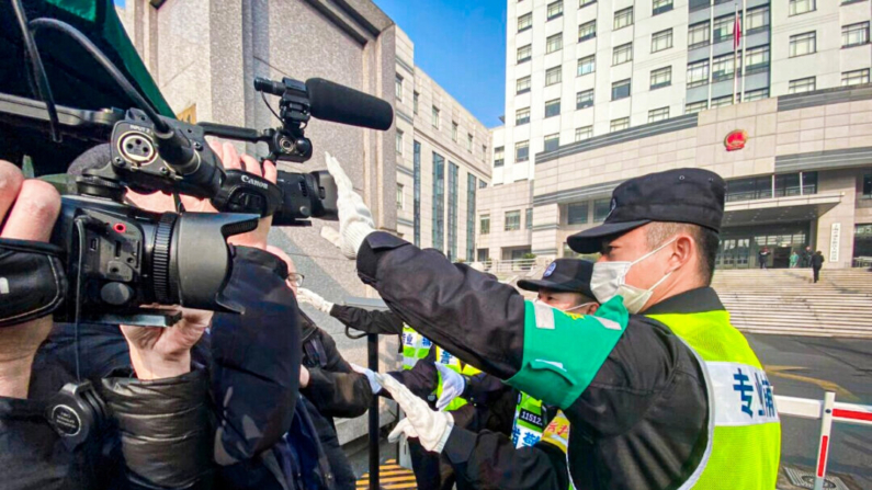 Um policial cobre uma câmera para impedir que jornalistas gravem imagens do lado de fora do Tribunal Popular do Novo Distrito de Shanghai Pudong, onde o cidadão  jornalista chinês Zhang Zhan foi julgado em Xangai em 28 de dezembro de 2020 (Leo Ramirez/AFP via Getty Images)
