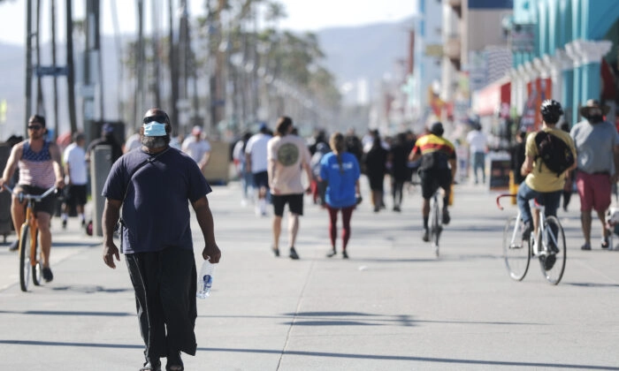Um homem usando uma máscara caminha pelo calçadão de Venice Beach no dia em que o condado de Los Angeles reabriu suas praias, que haviam sido fechadas devido à pandemia de COVID-19, na Califórnia, em 13 de maio de 2020. (Mario Tama/Getty Images)
