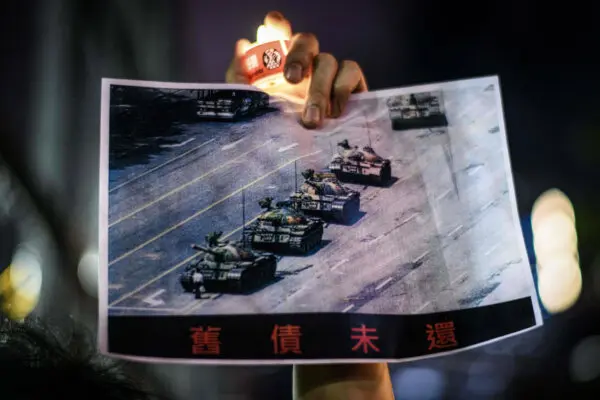 Um homem segura um pôster do famoso “Homem do Tanque” em frente aos tanques militares chineses na Praça Tiananmen, em Pequim, em 5 de junho de 1989, durante uma comemoração do evento da Praça Tiananmen de 1989, no Victoria Park, em Hong Kong, em 4 de junho de 2020. (Anthony Wallace/AFP via Getty Images)