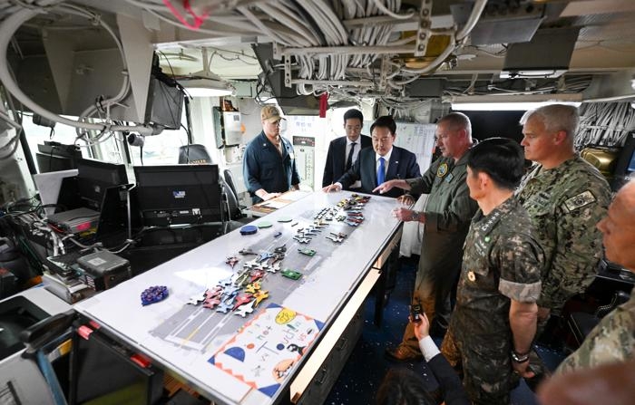Uma foto disponibilizada pelo gabinete presidencial sul-coreano mostra o presidente Yoon Suk Yeol (3-esq.) ouvindo explicações na sala de controle do convés de voo do porta-aviões de propulsão nuclear 'USS Theodore Roosevelt' na base naval sul-coreana na cidade de Busan, no sudeste do país, em 25 de junho de 2024. O porta-aviões entrou na base três dias antes para participar do primeiro exercício militar trilateral multidomínio, "Freedom Edge", envolvendo a Coreia do Sul, os Estados Unidos e o Japão (EFE/EPA/Gabinete Presidencial HANDOUT COREIA DO SUL)