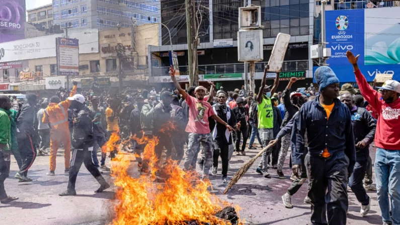 Manifestantes reagem ao lado de pneus em chamas durante um protesto contra a lei financeira em Nairóbi, Quênia, em 25 de junho de 2024. (Patrick Meinhardt/Getty Images)
