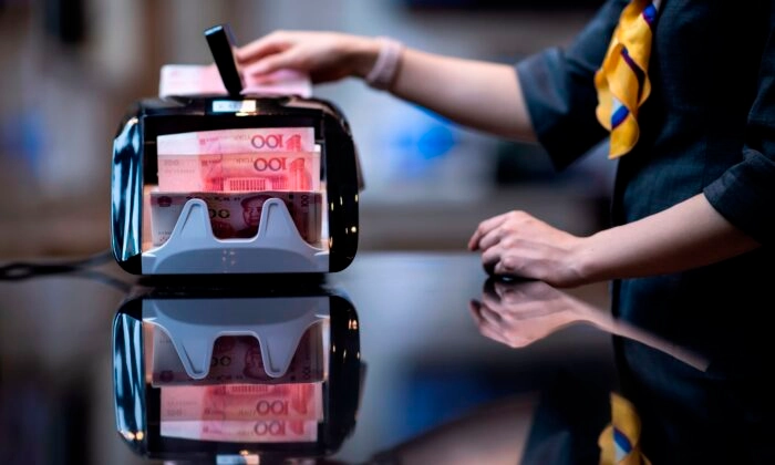 Um funcionário de banco usa uma máquina de contar dinheiro para contar notas de 100 yuans em um banco em Xangai, na China, em uma foto de arquivo. (Johannes Eisele/AFP via Getty Images)
