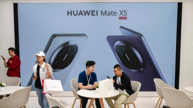 Um cliente fala com um funcionário enquanto retira um novo smartphone Mate 60 em uma loja principal da Huawei depois que a empresa apresentou novos produtos em Pequim, China, em 25 de setembro de 2023. (Kevin Frayer/Getty Images)

