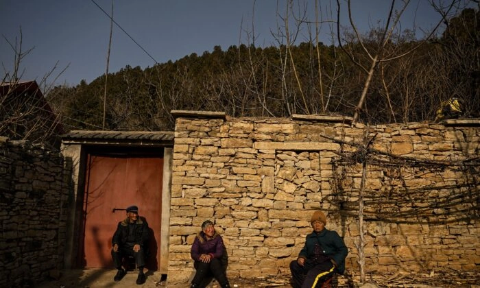 Idosos sentados em frente a uma casa em uma área rural em Tai'an, província de Shandong, no leste da China, em 7 de janeiro de 2023. (Noel Celis/AFP via Getty Images)