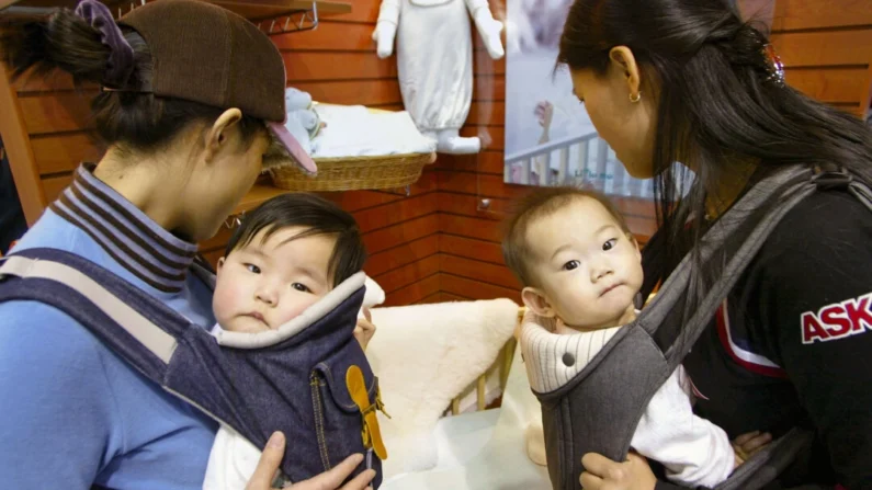 Duas mães carregam seus bebês em uma exposição sobre gravidez e maternidade em Seul, Coreia do Sul, em 17 de fevereiro de 2005. (Chung Sung-Jun/Getty Images)
