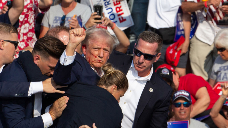 O candidato republicano Donald Trump é visto com sangue no rosto, cercado por agentes do serviço secreto, enquanto é retirado do palco em um evento de campanha na Butler Farm Show Inc. em Butler, Pensilvânia, em 13 de julho de 2024 (Foto de REBECCA DROKE/AFP via Getty Images)