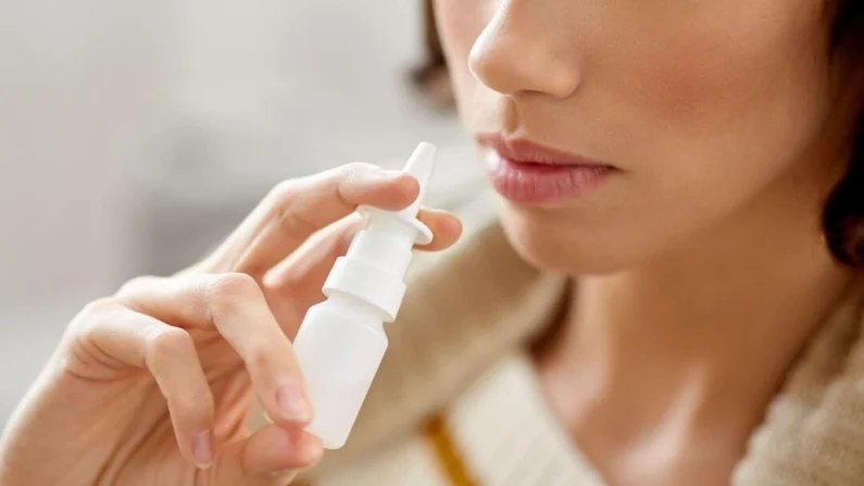 Uma mulher segura um frasco de spray nasal. (Foto de fundo/Shutterstock)
