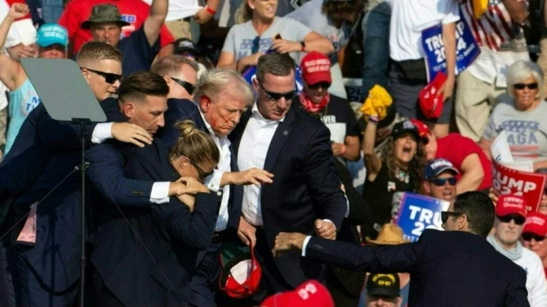 O ex-presidente republicano Donald Trump é visto com sangue no rosto cercado por agentes do serviço secreto ao ser retirado do palco em um evento de campanha no Butler Farm Show Inc. em Butler, Pensilvânia, em 13 de julho de 2024. (Rebecca Droke/ AFP via Getty Images)