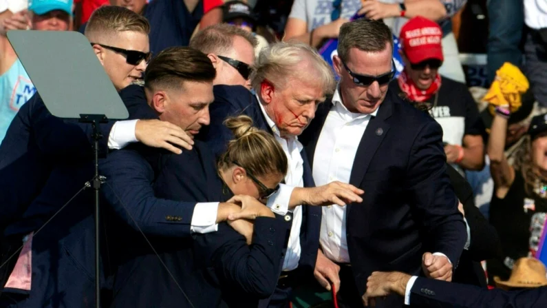 O ex-presidente Donald Trump com sangue no rosto cercado por agentes do serviço secreto ao ser retirado do palco em um evento de campanha em Butler, Pensilvânia, em 13 de julho de 2024. (Rebecca Droke/AFP via Getty Images)
