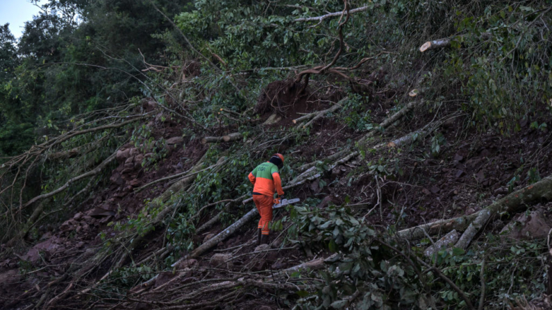 Um trabalhador corta árvores na estrada em Encantado, Estado do Rio Grande do Sul, Brasil, em 22 de maio de 2024 (Foto de NELSON ALMEIDA/AFP via Getty Images)