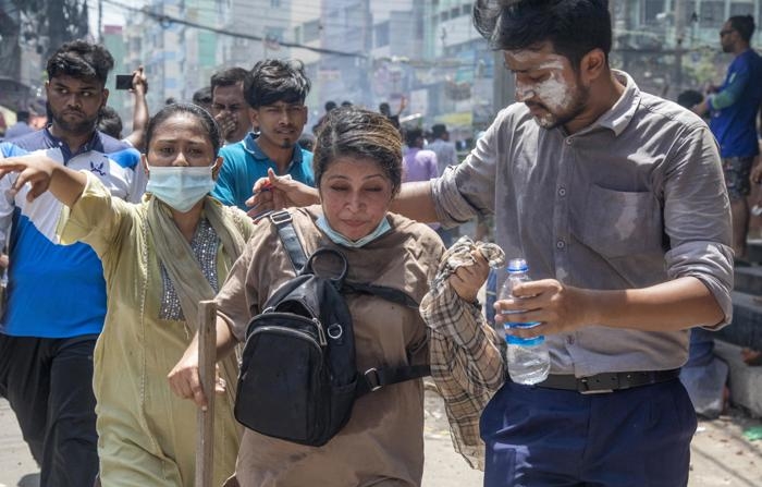 Uma pessoa ferida recebe assistência enquanto manifestantes entram em confronto com a polícia durante protestos estudantis em Dhaka, Bangladesh, em 18 de julho de 2024 (EFE/EPA/MONIRUL ALAM)