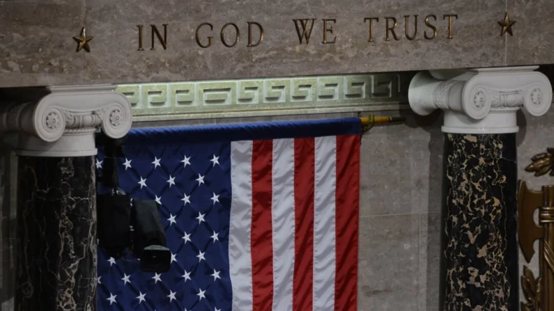 A bandeira dos EUA é vista pendurada sob as palavras “In God We Trust” na Câmara, no Capitólio, em Washington, em uma foto de arquivo. (Jewel Samad/AFP via Getty Images)