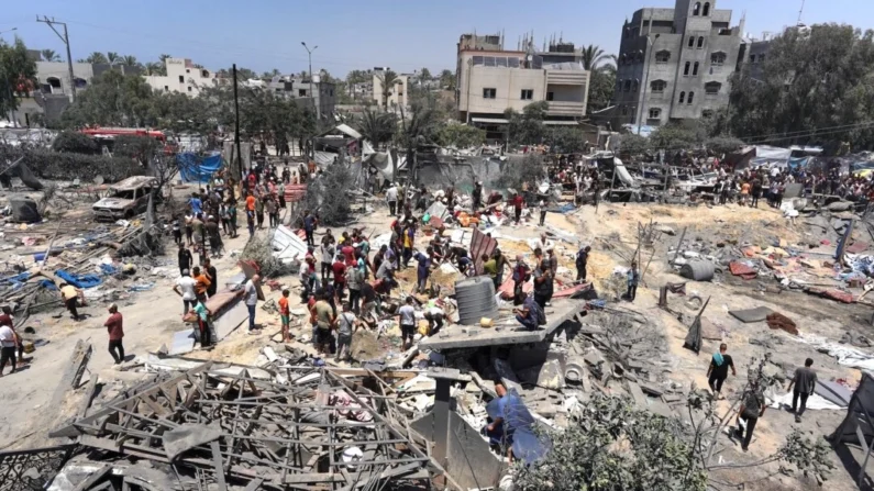 Moradores de Gaza observam os destroços de barracas destruídas e estruturas habitacionais improvisadas após um ataque militar israelense ao campo de al-Mawasi para deslocados internos, perto da cidade de Khan Yunis, no sul da Faixa de Gaza, em 13 de julho de 2024, no qual 90 pessoas foram mortas segundo as autoridades de saúde de Gaza. (Bashar Taleb/AFP via Getty Images)
