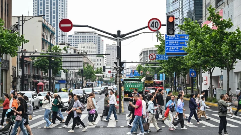 Pessoas atravessam uma rua no distrito de Huangpu em Xangai, China, em 6 de junho de 2024. (Hector Retamal /AFP via Getty Images)
