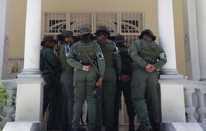 Membros da Polícia Militar da Venezuela impedem o acesso de jornalistas à seção eleitoral do Instituto Elena de Bueno, onde a líder da oposição venezuelana María Corina Machado votou no domingo em Caracas (EFE/Ronald Peña R.)