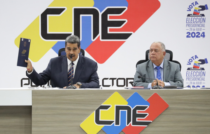 O ditador venezuelano Nicolas Maduro (à esquerda) fala com o presidente do Conselho Nacional Eleitoral (CNE), Elvis Amoroso, na segunda-feira (29), durante a entrega do ato de posse como presidente eleito, em Caracas na Venezuela (EFE/ Ronald Peña R.)