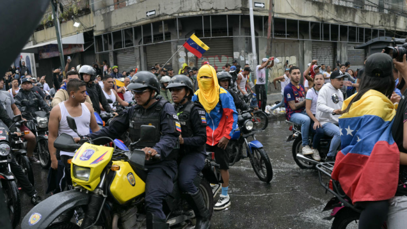 Policiais passam por manifestantes durante um protesto contra o governo do presidente venezuelano Nicolas Maduro em Caracas, em 29 de julho de 2024, um dia após a eleição presidencial venezuelana. Protestos irromperam em partes de Caracas na segunda-feira contra a vitória da reeleição reivindicada pelo presidente venezuelano Nicolas Maduro, mas contestada pela oposição e questionada internacionalmente, observaram jornalistas da AFP. (YURI CORTEZ/AFP via Getty Images)