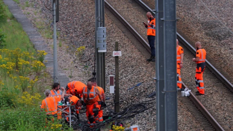 Trabalhadores ferroviários da SNCF e policiais trabalham no local onde vândalos atacaram a rede de trens de alta velocidade da França com uma série de ações coordenadas que causaram grandes transtornos, em Croisilles, norte da França, em 26 de julho de 2024. (Brian Snyder/Reuters)
