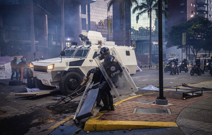 Membros da Guarda Nacional Bolivariana (GNB) entram em confronto com manifestantes por causa dos resultados da eleição presidencial em Caracas na segunda-feira (EFE/ Henry Chirinos)