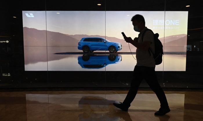 Um homem passa por um outdoor com o novo modelo Li Xiang One, da fabricante chinesa de carros elétricos Li Auto Inc., em um shopping center em Pequim, em 12 de agosto de 2021. (JADE GAO/AFP via Getty Images)
